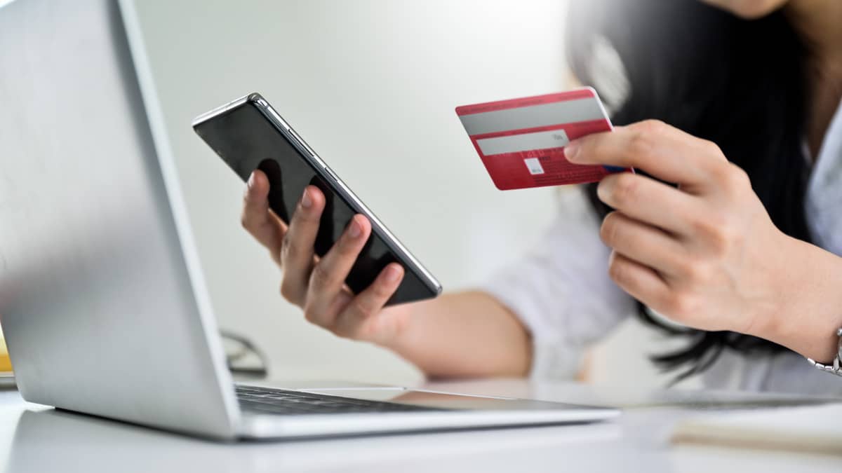 Person shopping online with phone and credit card.