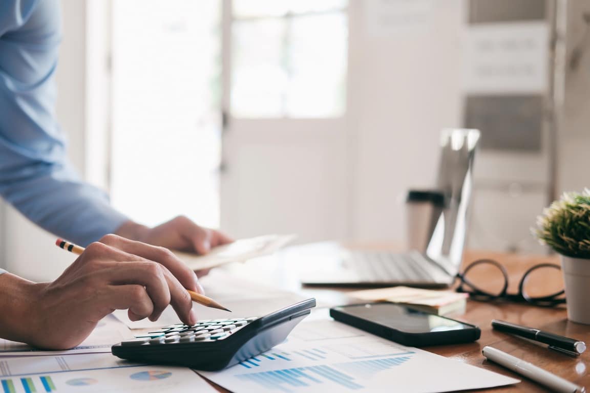 How to choose the right finance company in NZ, a person working through figures with a calculator at a desk